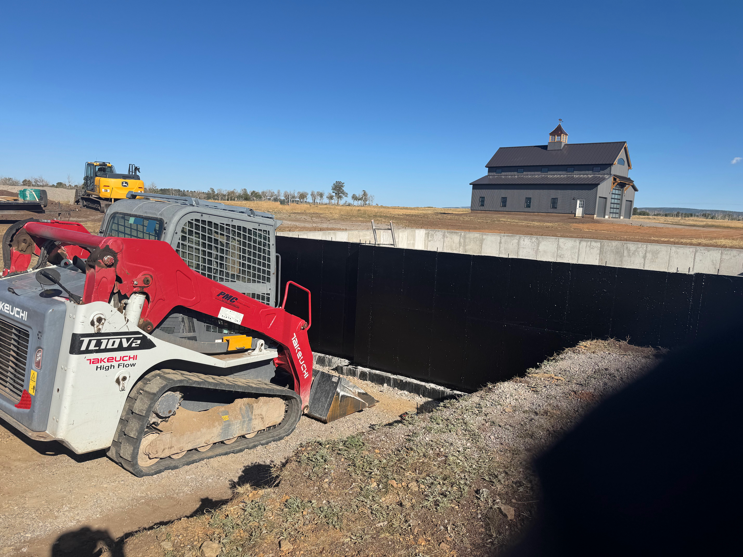 Foundation of the main house with custom built barn in the background.