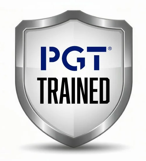 A shield emblem with the PGT logo and the words 'TRAINED' in black, showing Ambassador's aptitude as installers of impact-resistant hurricane windows and doors in the Tampa Bay Area.