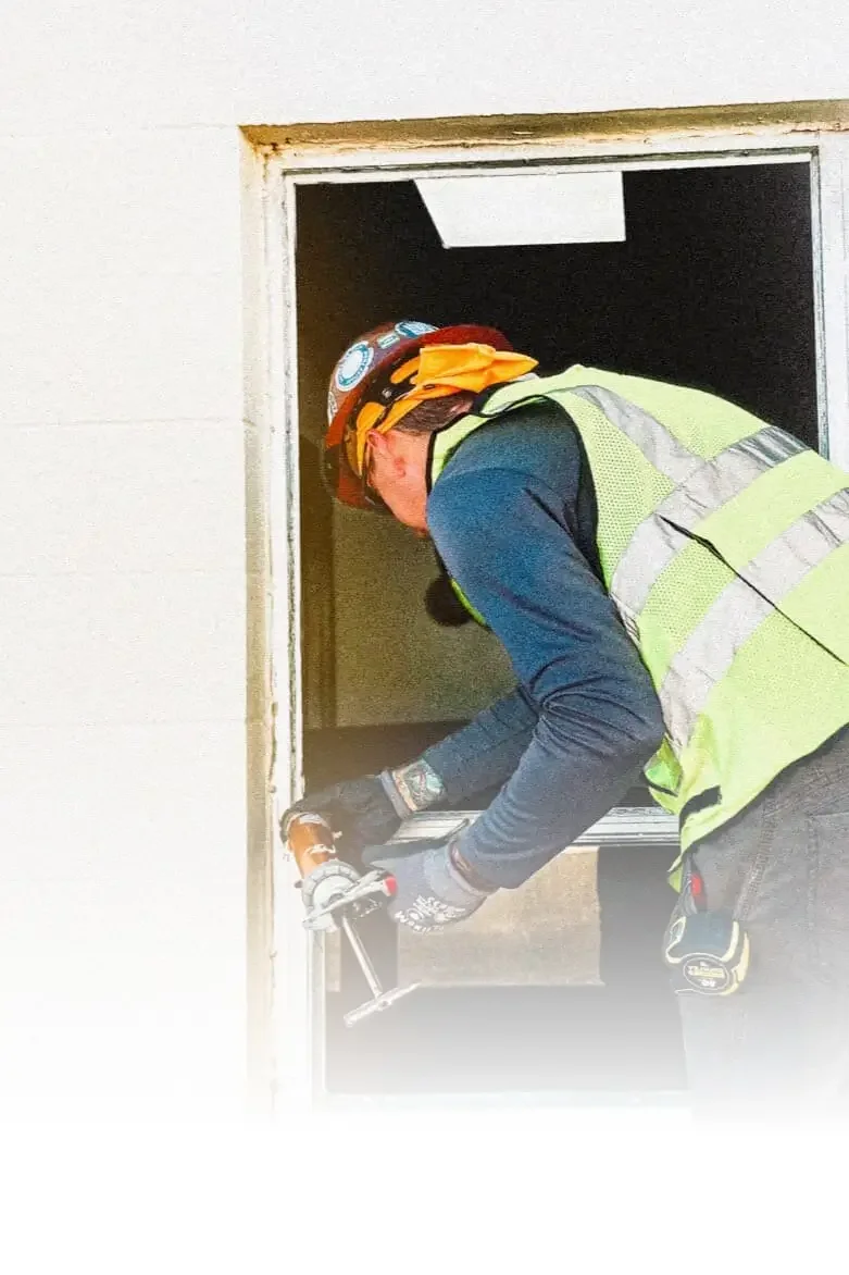 Ambassador Window and Doors technician in safety helmet and vest installing hurricane impact windows and doors at MacDill Air Force Base in Pinellas County, Florida.