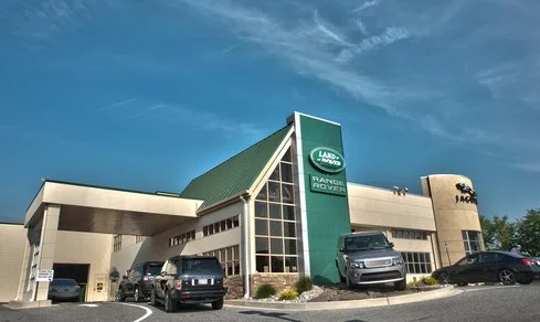 Land Rover dealership building with cars parked in front under a blue sky