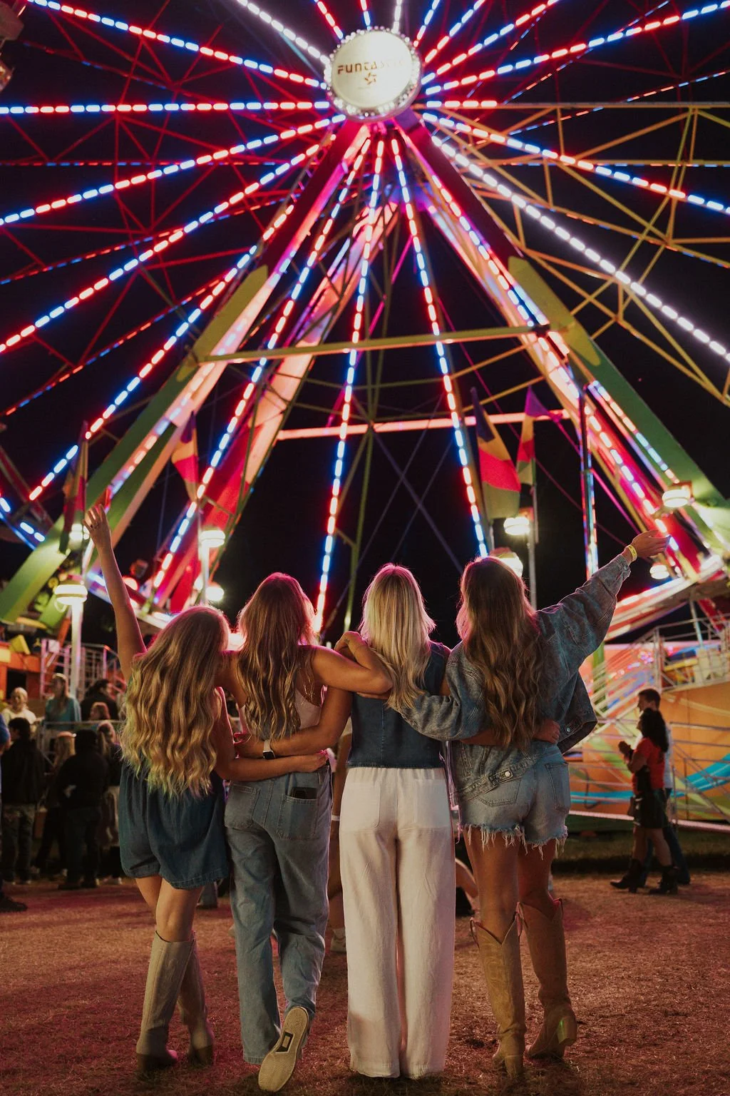 Friends enjoying a night together at a fair, representing the connection behind intentional hair color by Destinee Horat