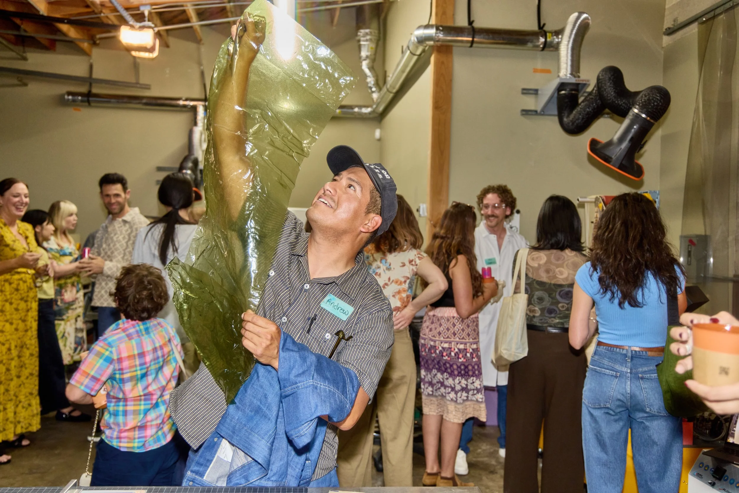 An event attendee wearing Unwaste reusable name tags looking at Sway's seaweed-derived packaging film, showcasing sustainable materials replacing single-use plastic.