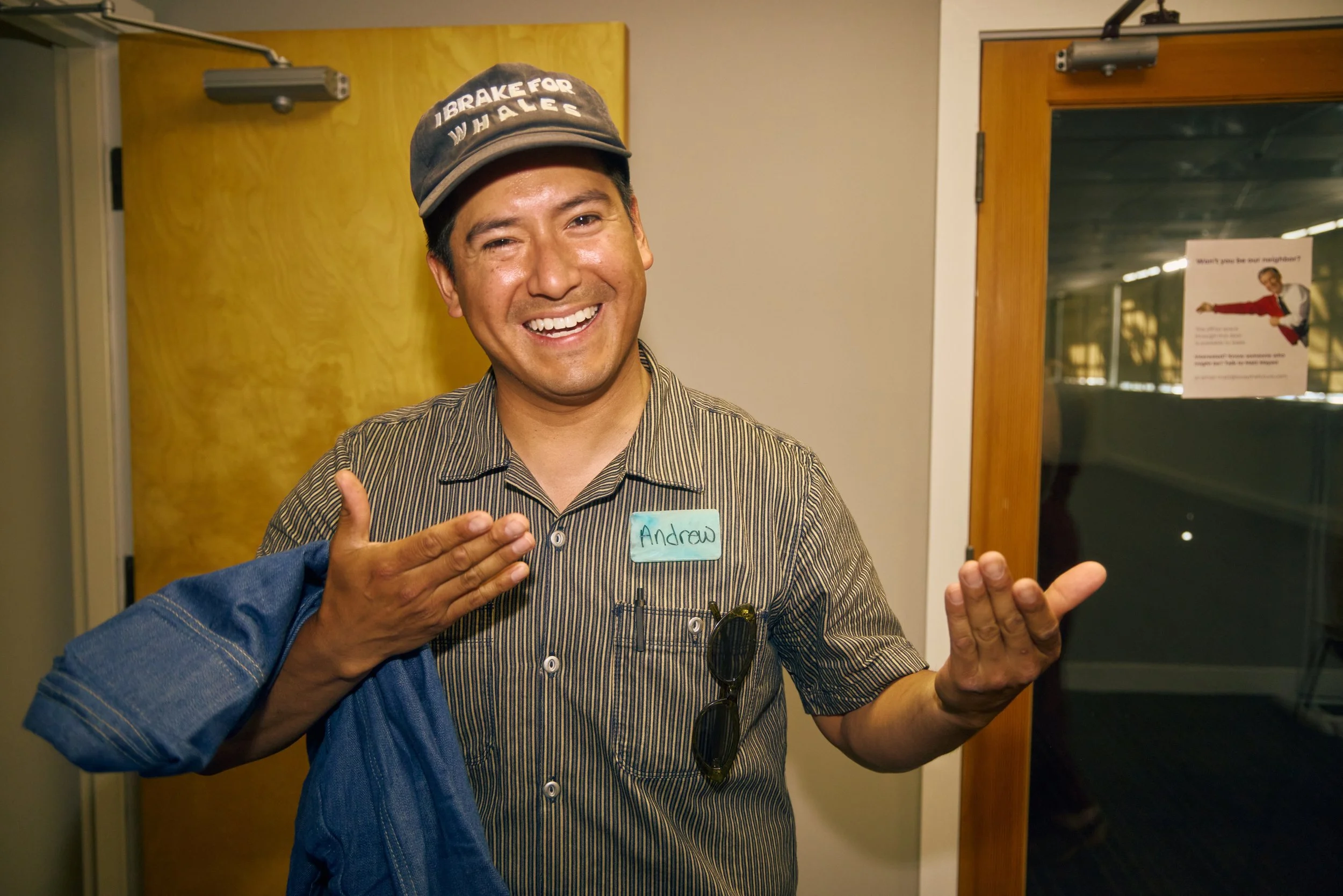 A guest wearing an Unwaste reusable name tag laughs during a networking event, part of Unwaste's rental program for sustainable conference and event badges.