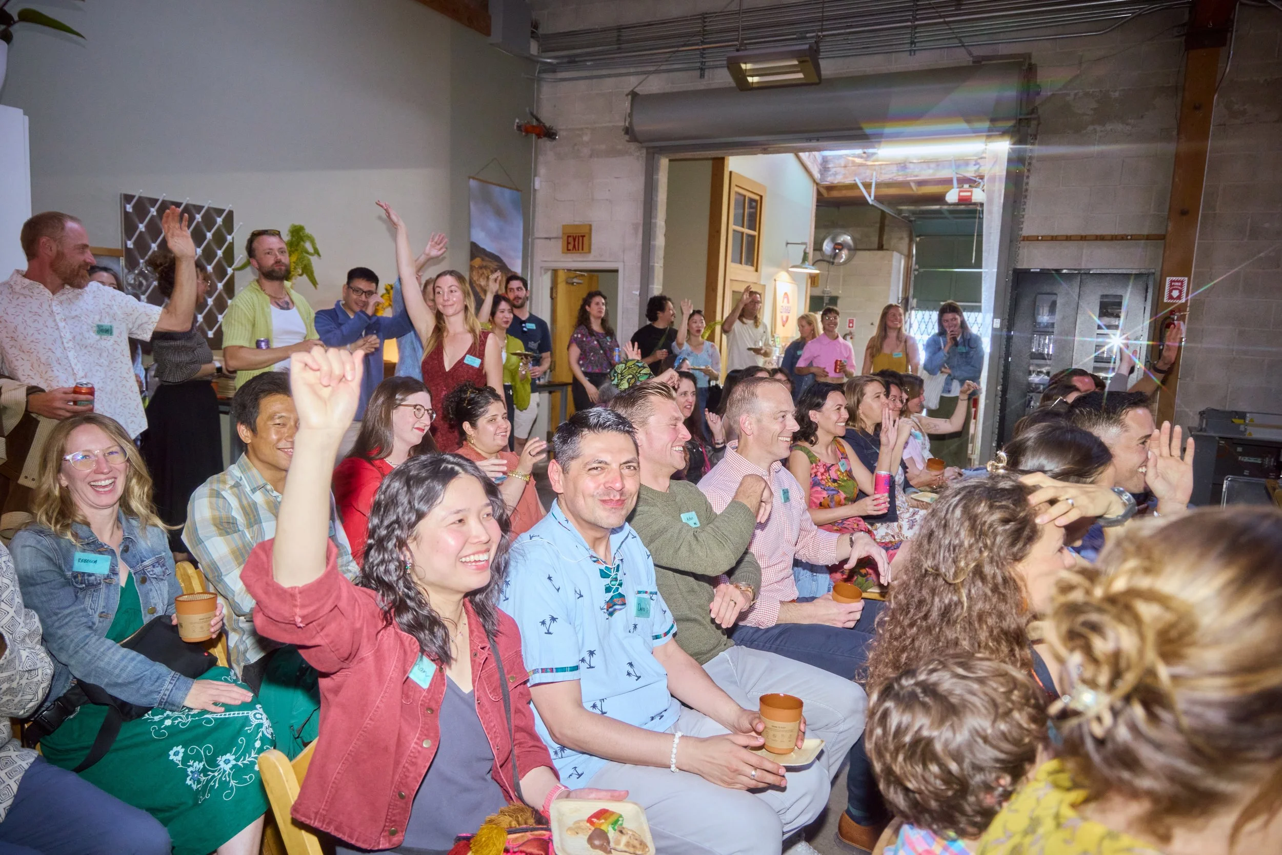 Attendees wearing Unwaste reusable name tags cheer during Sway's headquarters celebration, where 60 rental name tags replaced disposable sticker badges for the event.