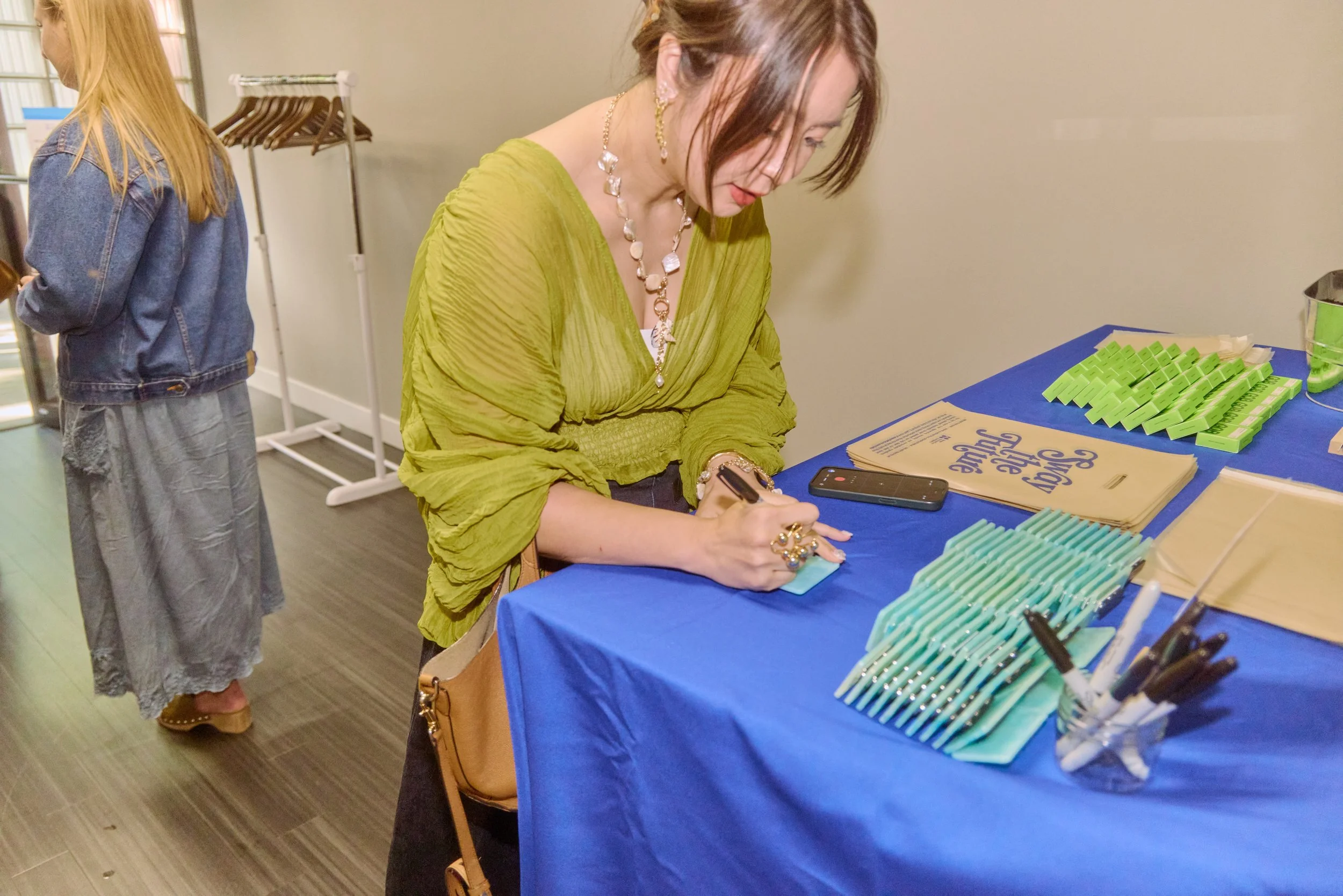 An attendee personalizes her reusable Unwaste name tag with a marker before a panel discussion, an eco-friendly alternative to disposable paper or plastic badges.