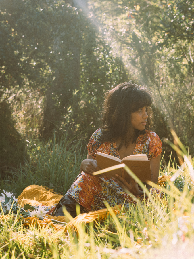 indian woman reading book in grass