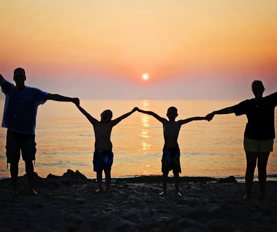 Family holding hands on the beach during sunset
