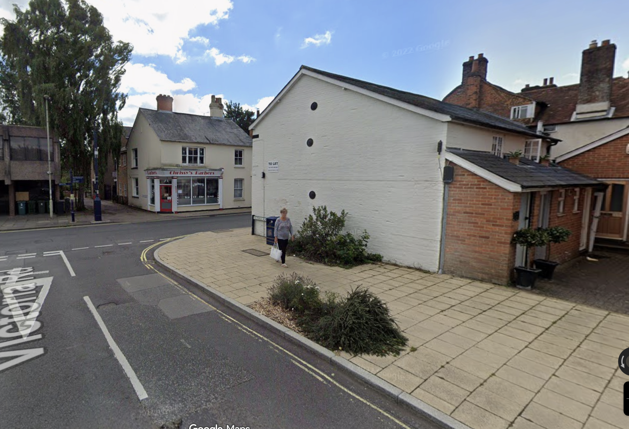 Street corner showing Pure Therapy room entrance a white building with round windows, plants.