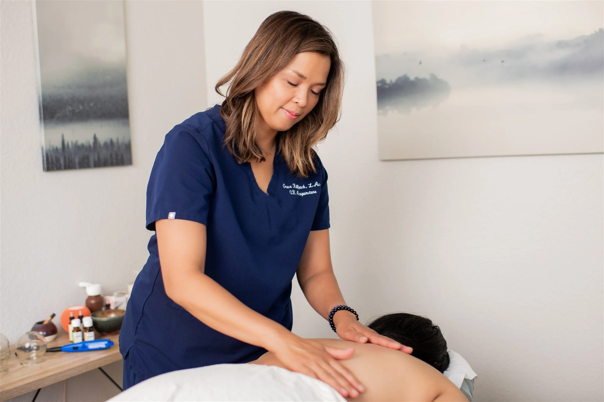 Acupuncturist Grace Killpack performing a deep healing for pain relief on a woman's back at her clinic Apo Acupuncture near Lafayette, CA.