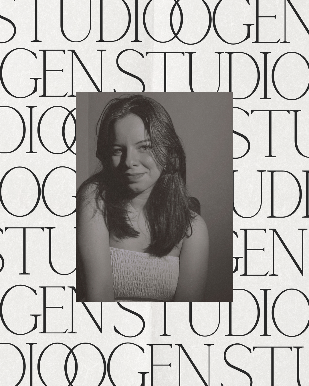 Retrato en escala de grises de una mujer sonriendo, con cabello largo y oscuro, usando un top blanco, frente a un fondo con letras en negrita que dice 'Studio Gens'.