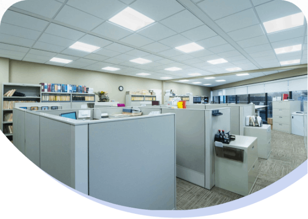 Empty office cubicles with filing cabinets and office supplies in a modern open-plan workspace.