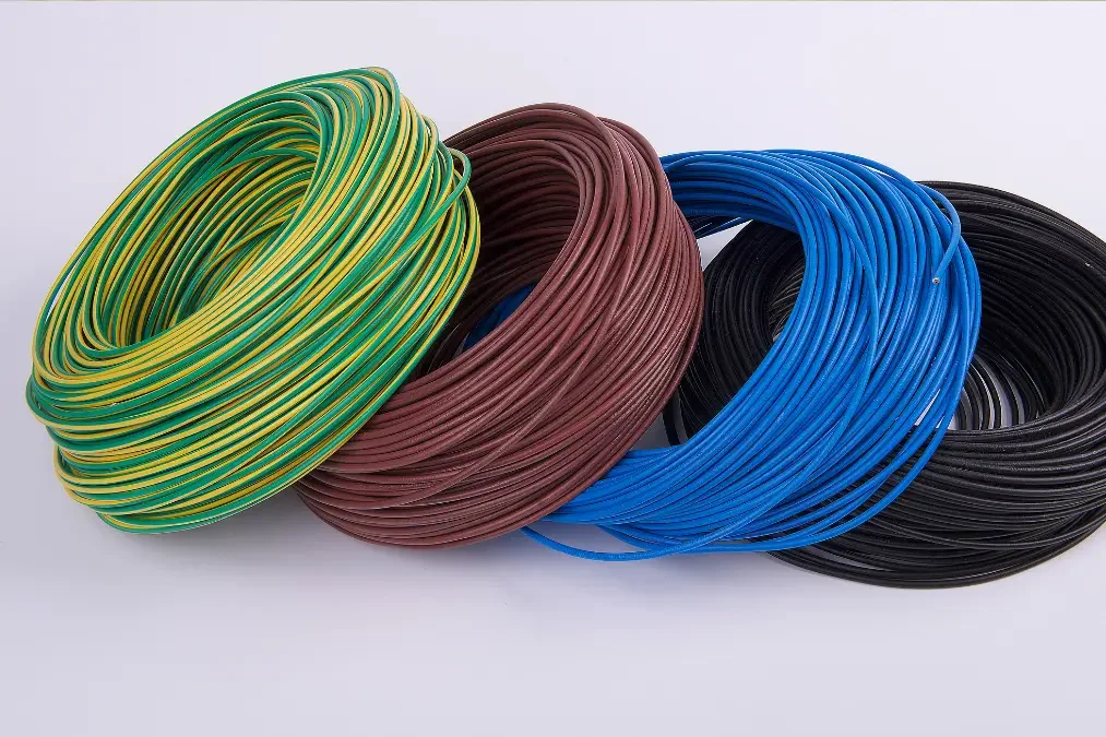 Coils of colored electrical wire in yellow and green, brown, blue, and black, arranged in a row on a white background.