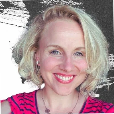 Emily Martin, Consultant | A woman with blonde hair smiling, wearing a pink and black striped top and earrings.