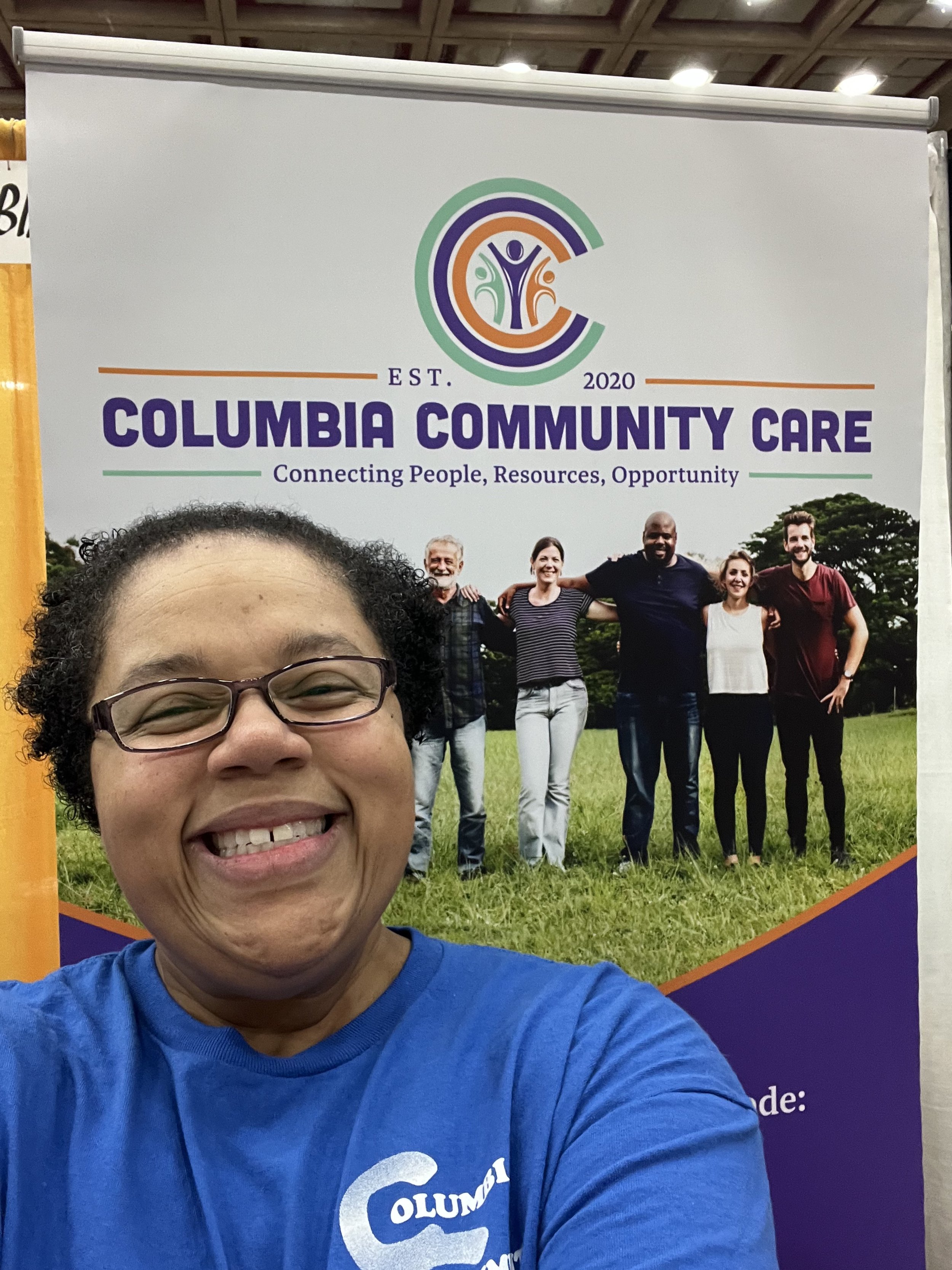 Jessica Nichols smiling in front of a banner for Columbia Community Care