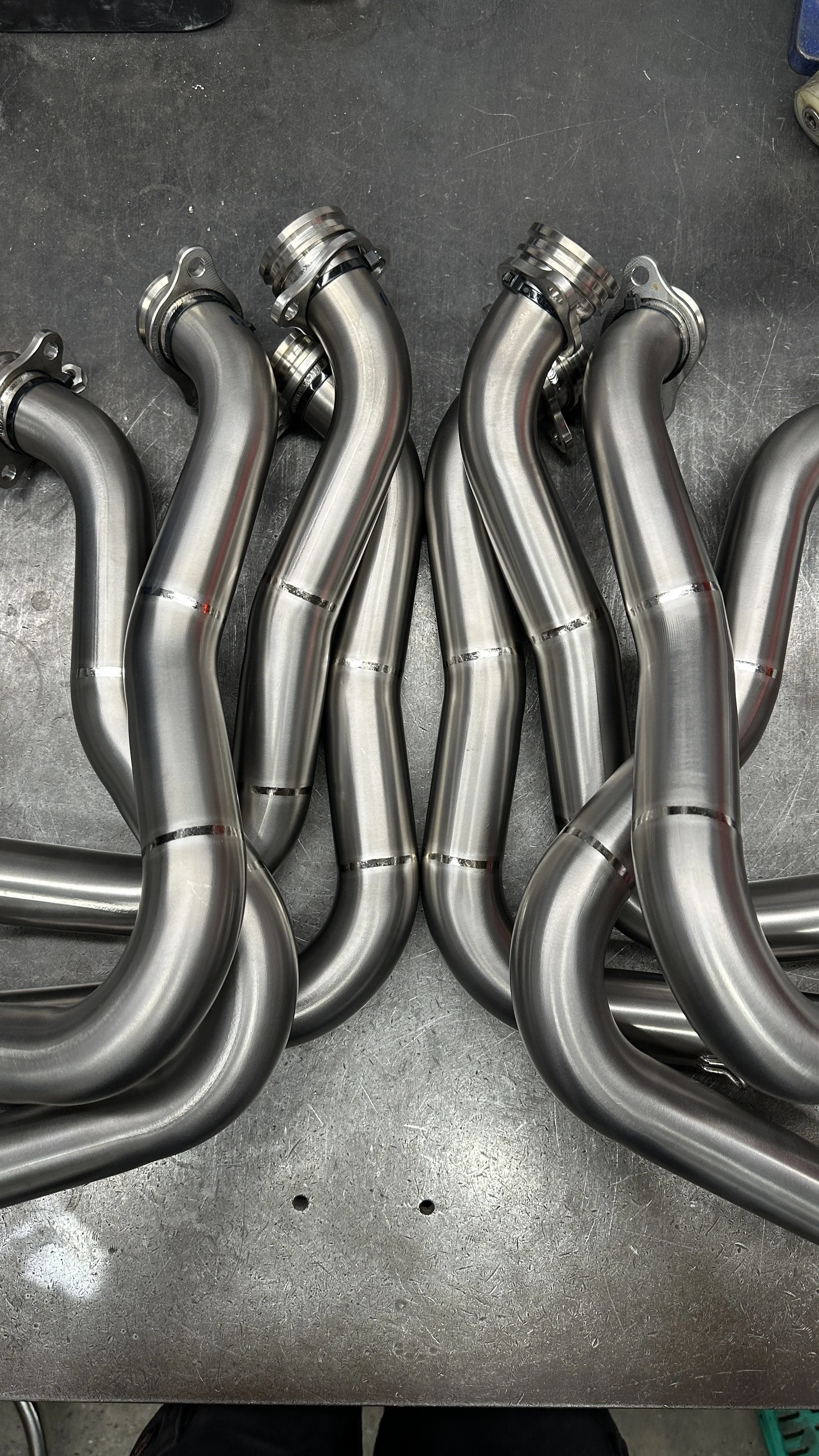 Several shiny metal automotive exhaust pipes on a workbench.