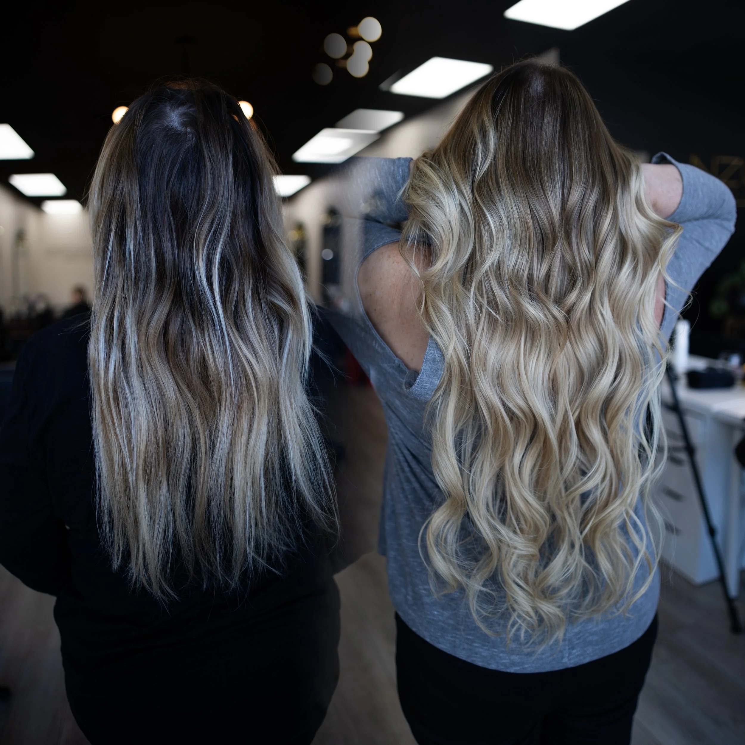 Two women with long, wavy blonde hair in a hair salon.