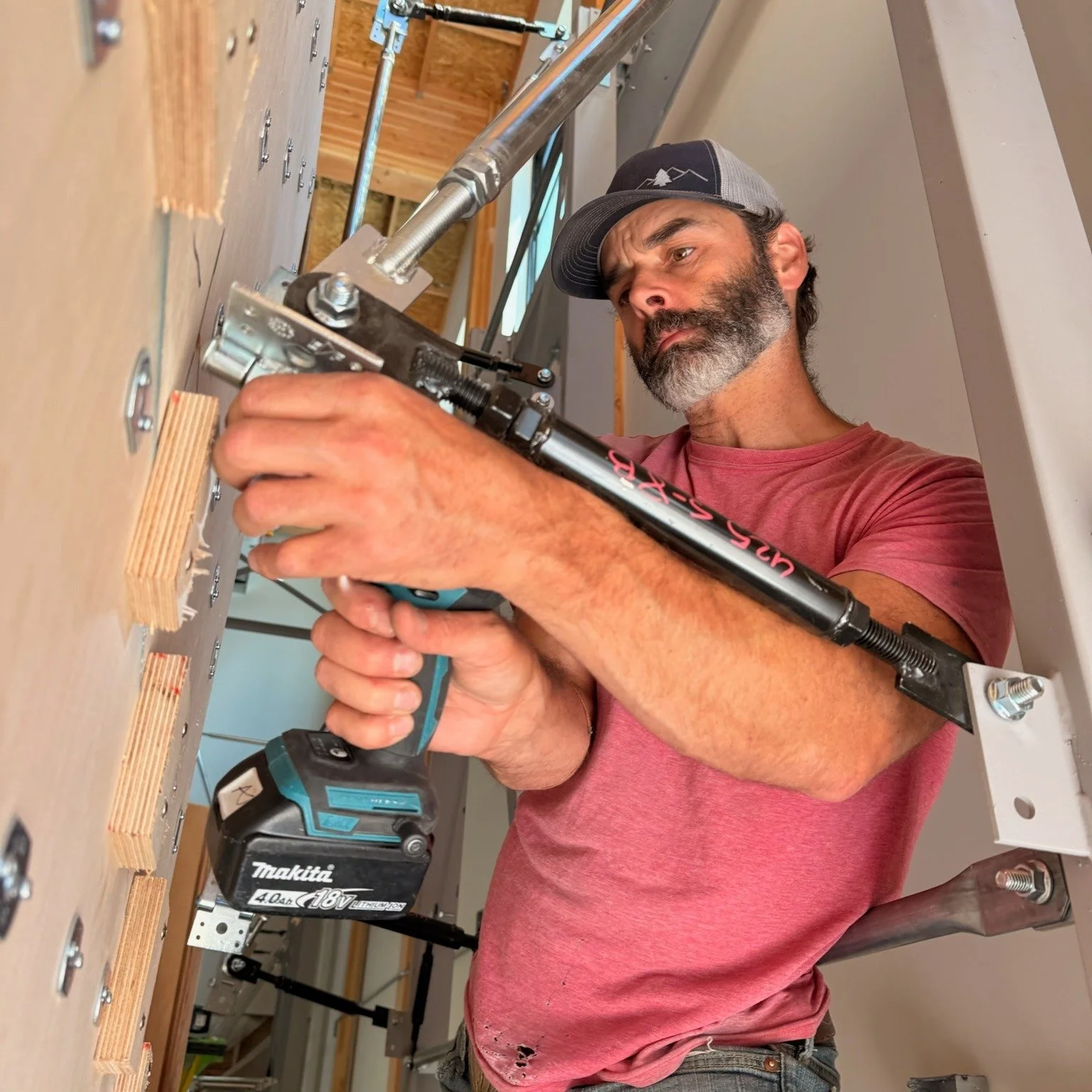 A builder fastening climbing-wall panels at Methow Spires in June 2026.