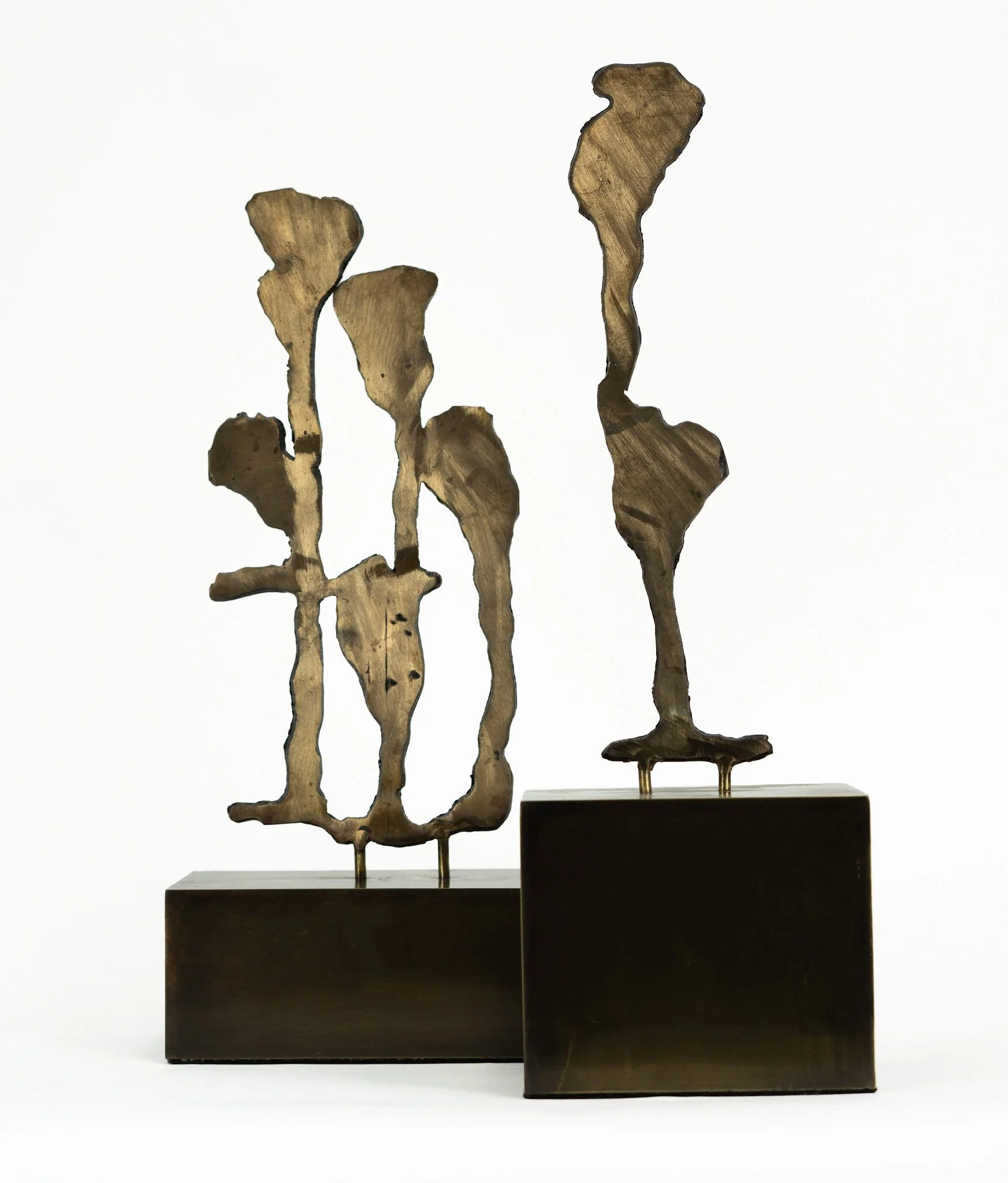Two abstract sculptures made of wood with dark bases, featuring irregular shapes and elongated forms, displayed against a white background.