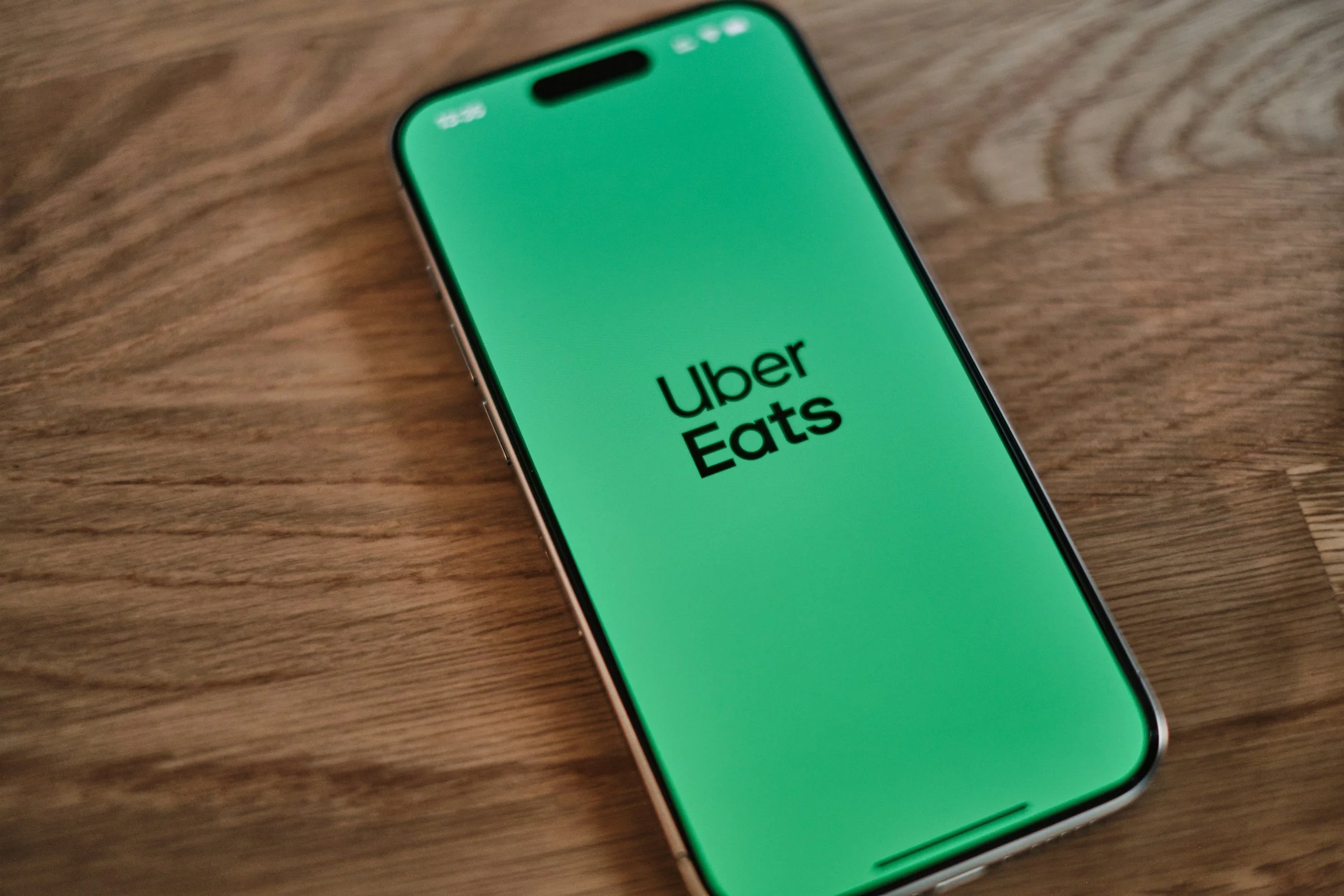 Smartphone with Uber Eats app open on the screen, placed on a wooden surface.
