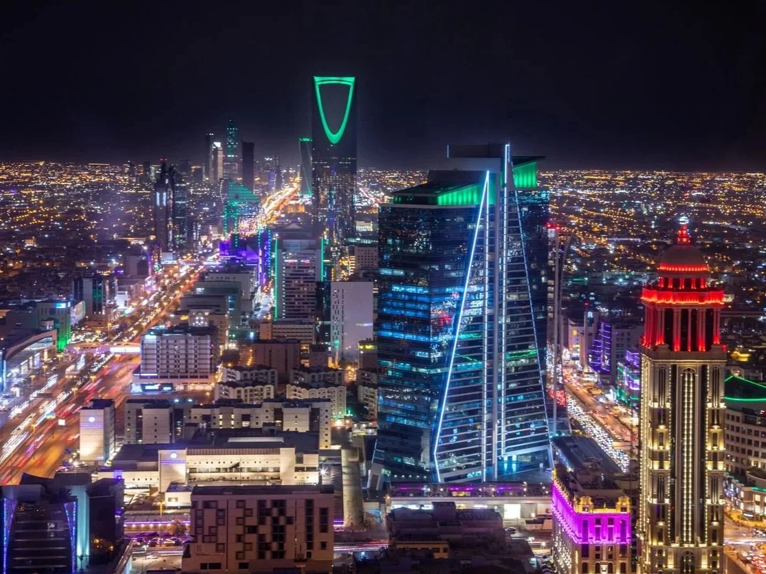 Nighttime cityscape of a modern Riyadh with illuminated skyscrapers and bright lights in Saudi Arabia.