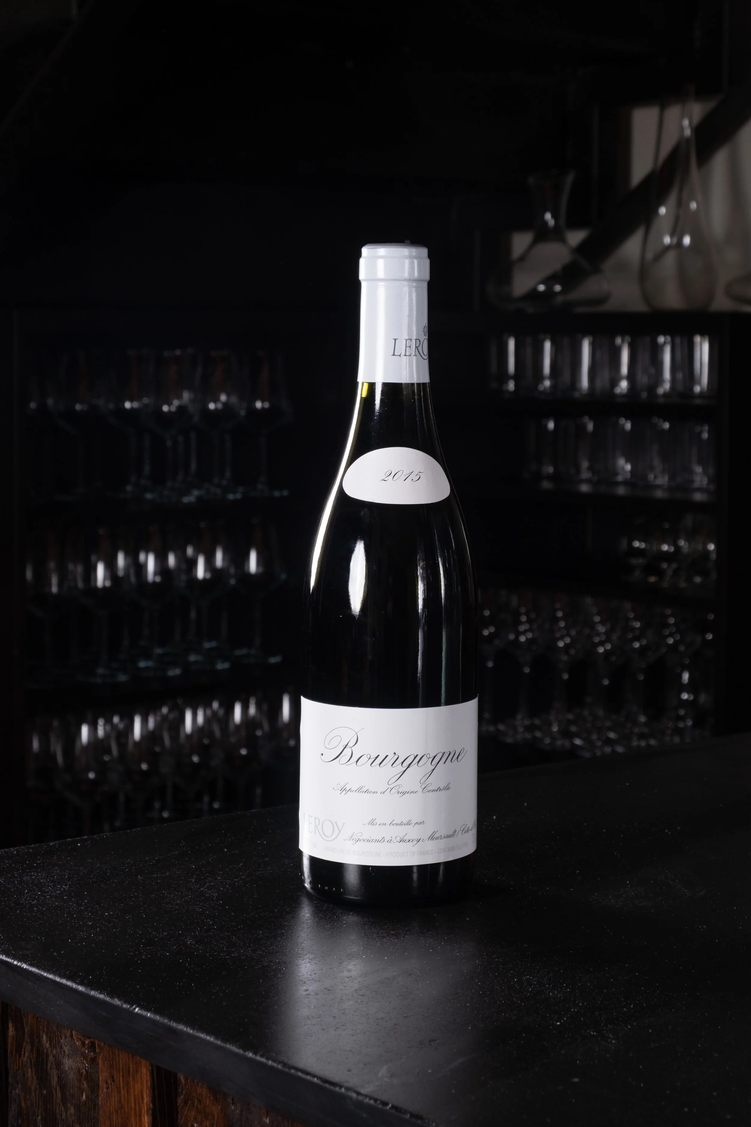 Una bottiglia di vino Bottiglia di vino di Borgogna sulla superficie di un bar, sfondo con bicchieri e attrezzature da bar