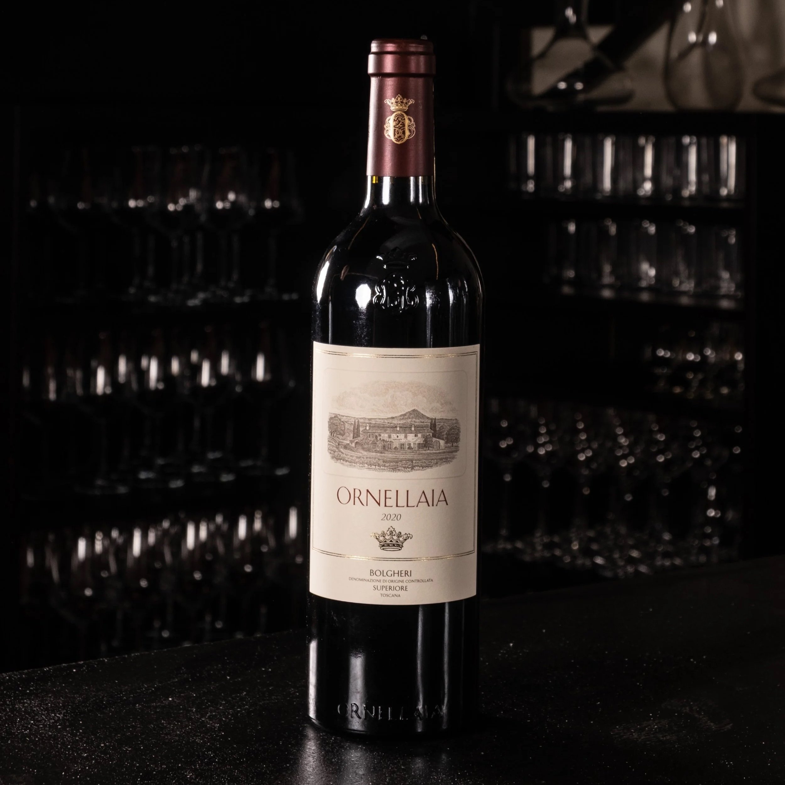 Bottiglia di vino rosso Orchidea di annata 2020 su un bancone, sfondo con bicchieri su scaffali.