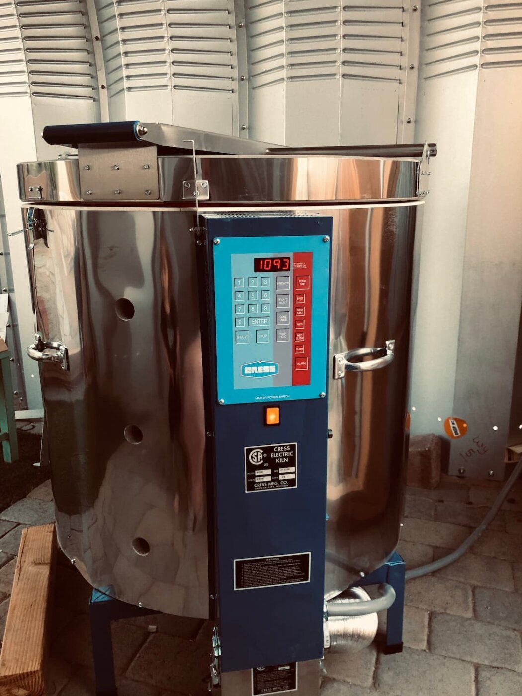A large, shiny stainless steel industrial machine with a control panel on the front displaying the number 1093. The machine is situated indoors on a tiled floor, with other equipment and metal panels visible in the background.