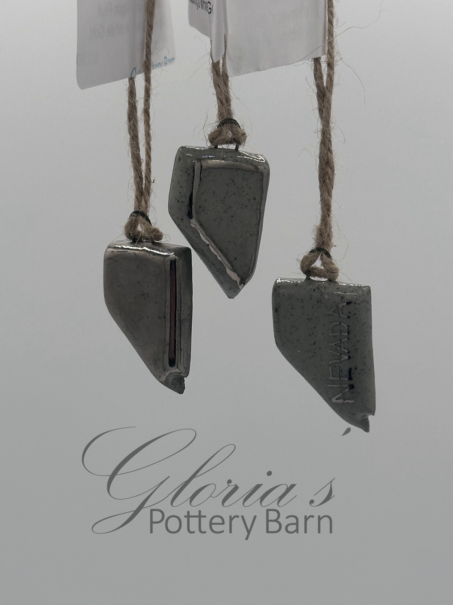 Three hanging ceramic pieces on rope with text reading 'Gloria's Pottery Barn' underneath.