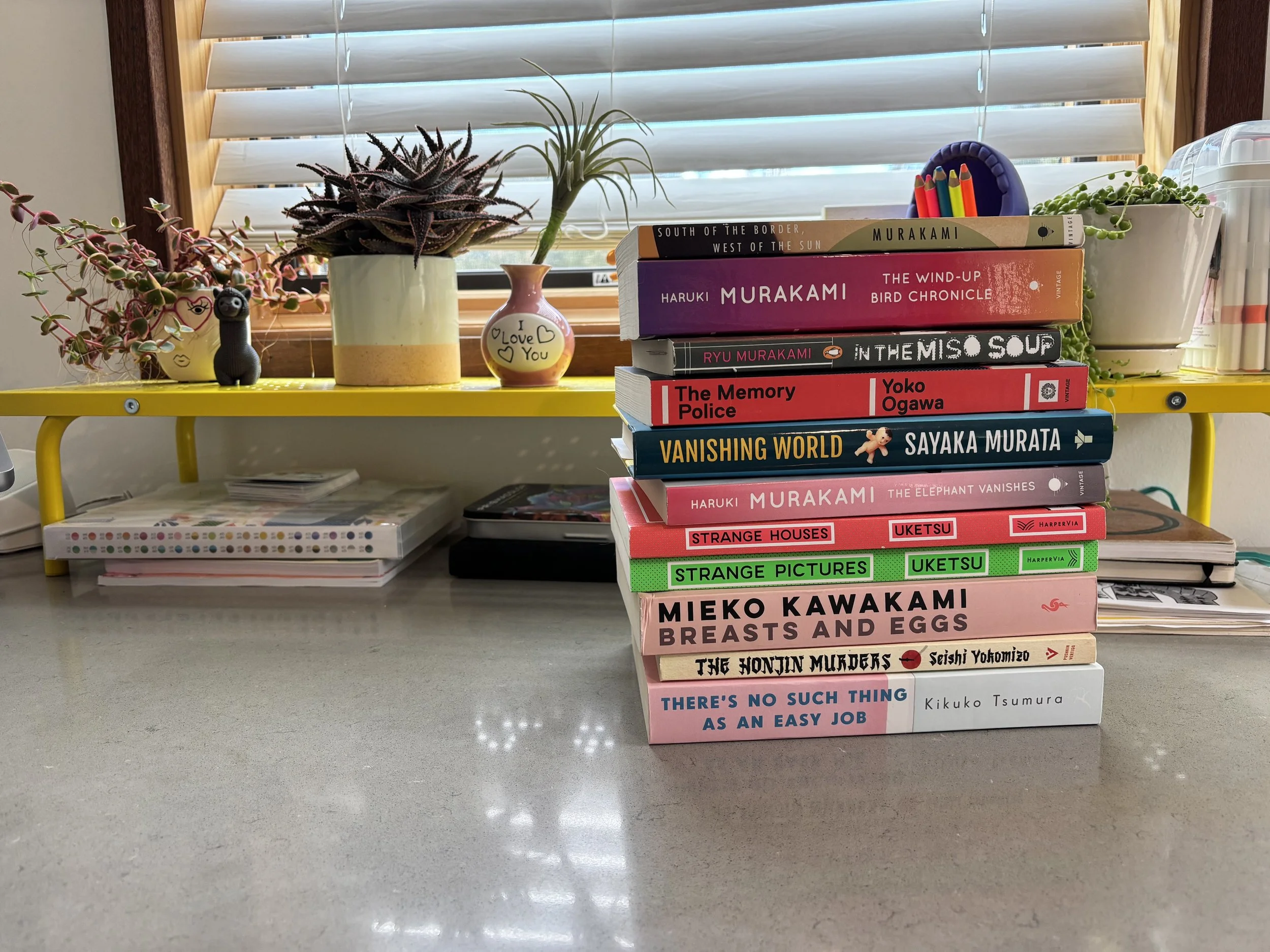 A stack of Japanese literature books on a desk.