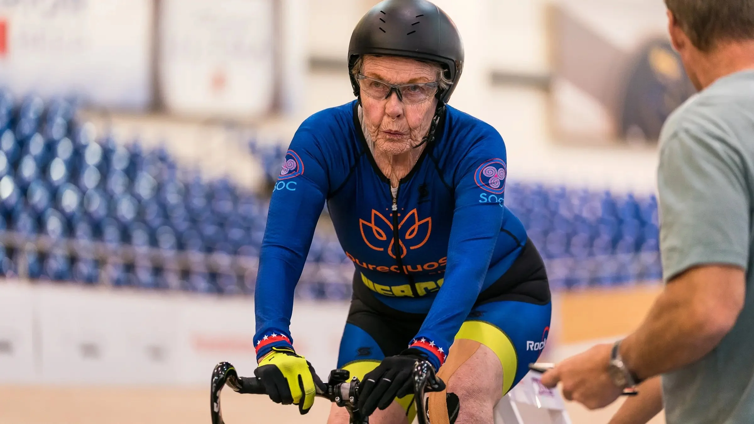 Cyclist Patricia Baker on her track bike in a velodrome.