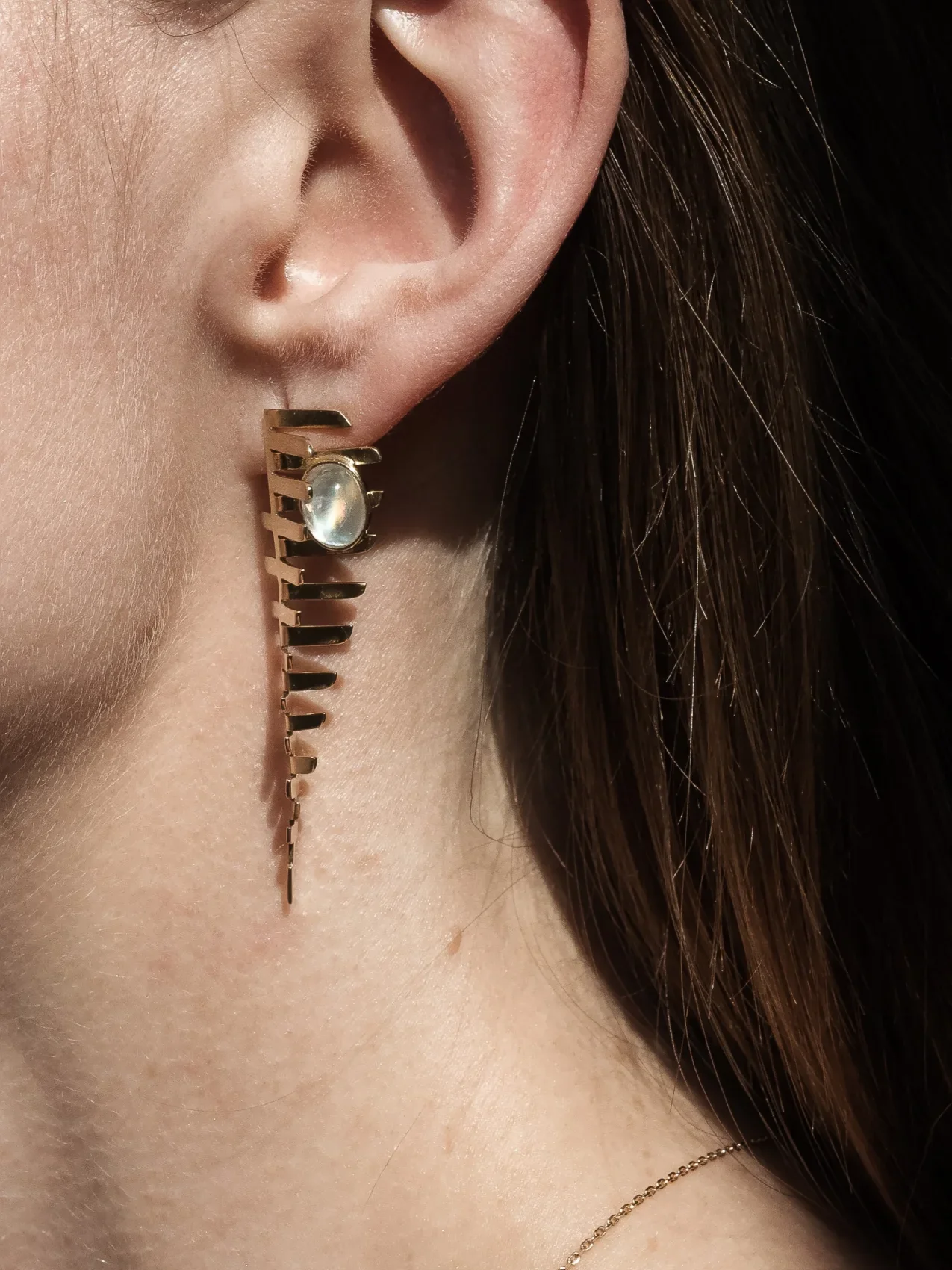 Pozlacené náušnice s měsíčním kamenem na uchu