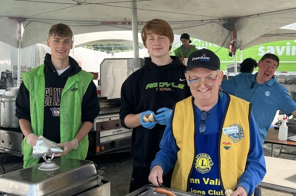 Two teenager boys from the Argyle Pipers football team helping out at Lynn Valley Days with Lions David and Eric Miura