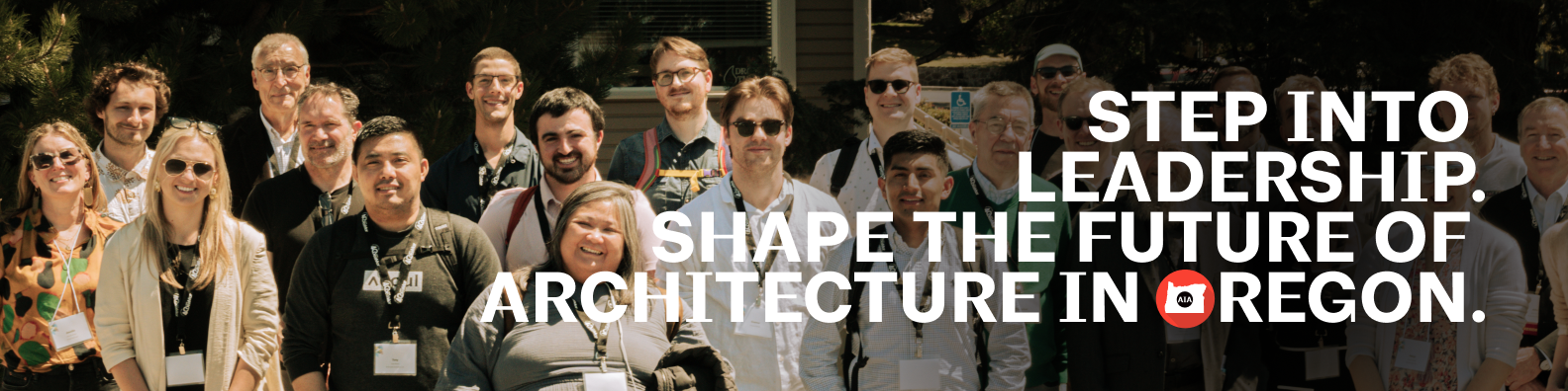 Group of diverse people standing outdoors in front of greenery and a building, wearing conference badges and smiling.