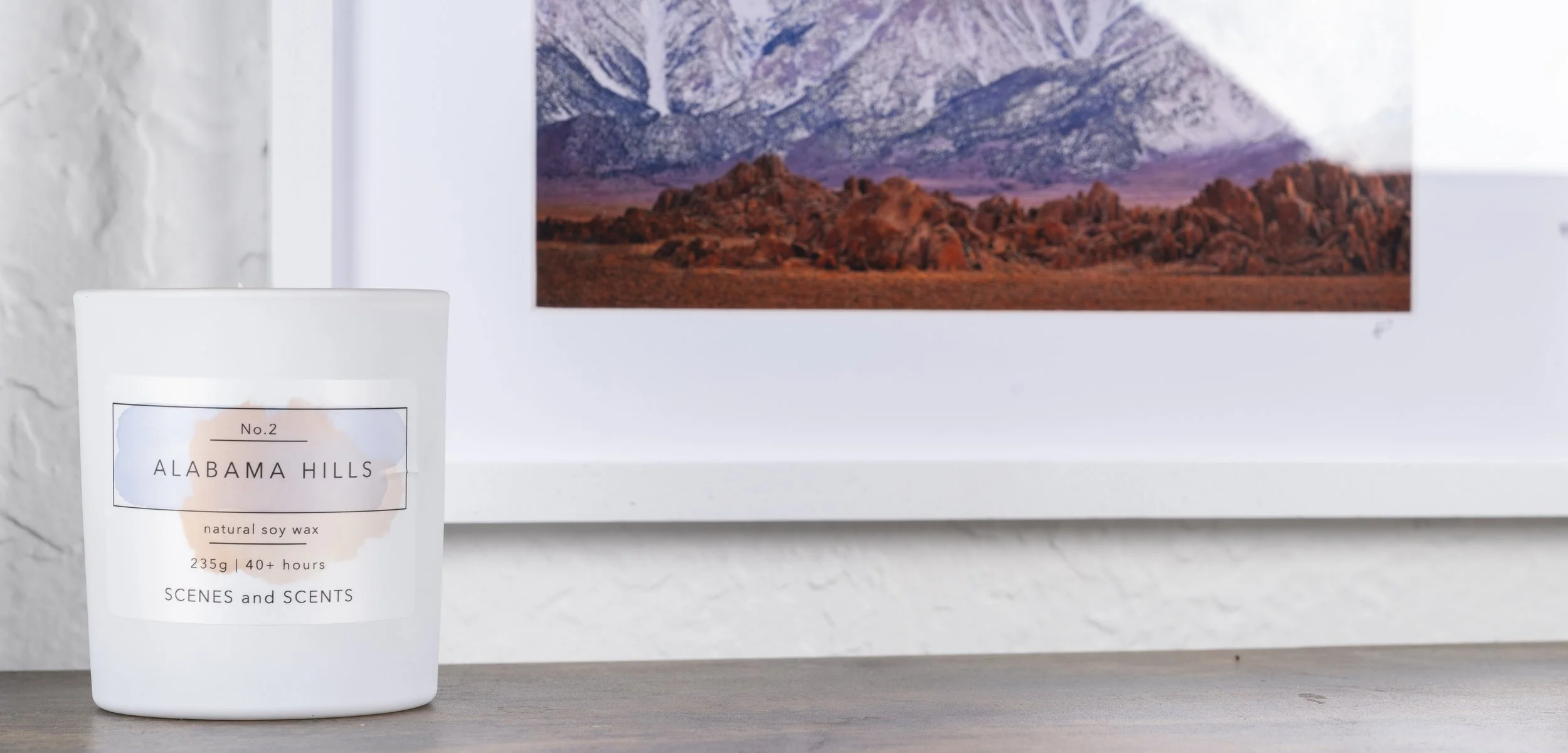 A white candle labeled 'Alabama Hills' with a mountain landscape in the background.
