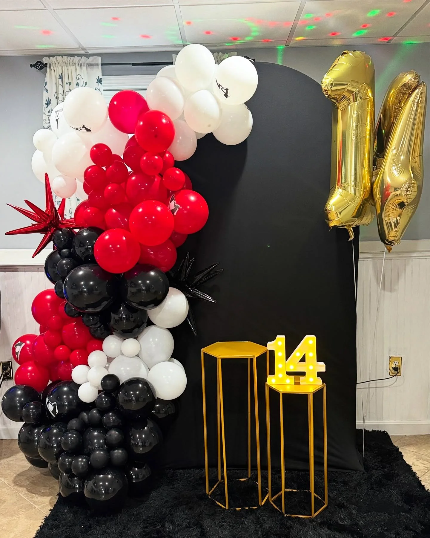 Stepping up in style! This birthday celebration gets bold vibes from a black, red, and white sneaker-themed balloon arch! 💥