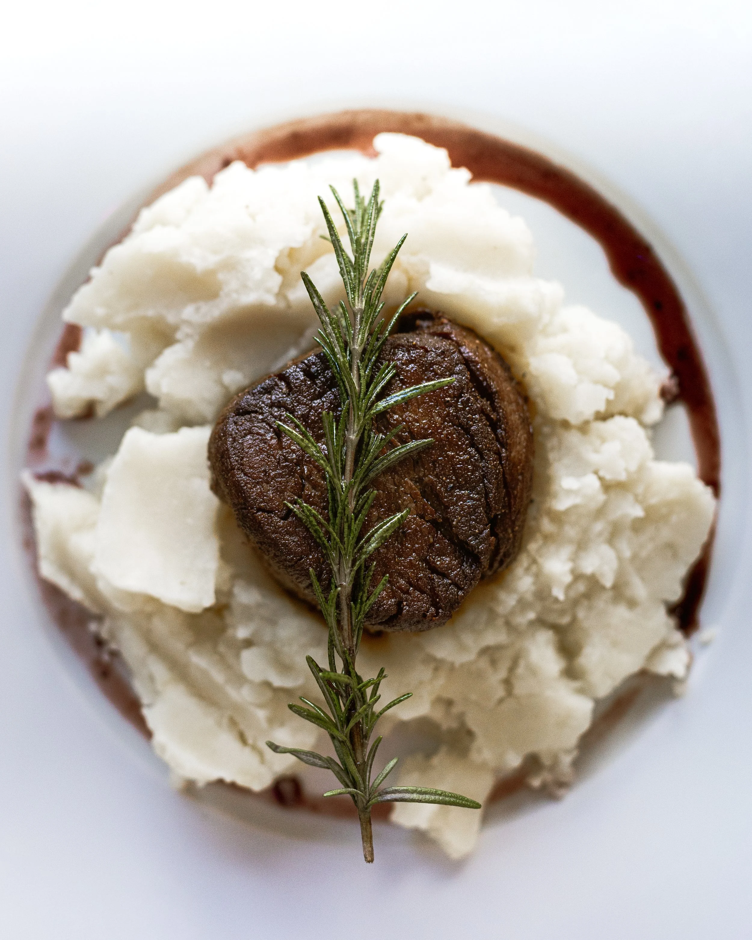 Baked meatloaf topped with mashed potatoes and garnished with a sprig of rosemary.