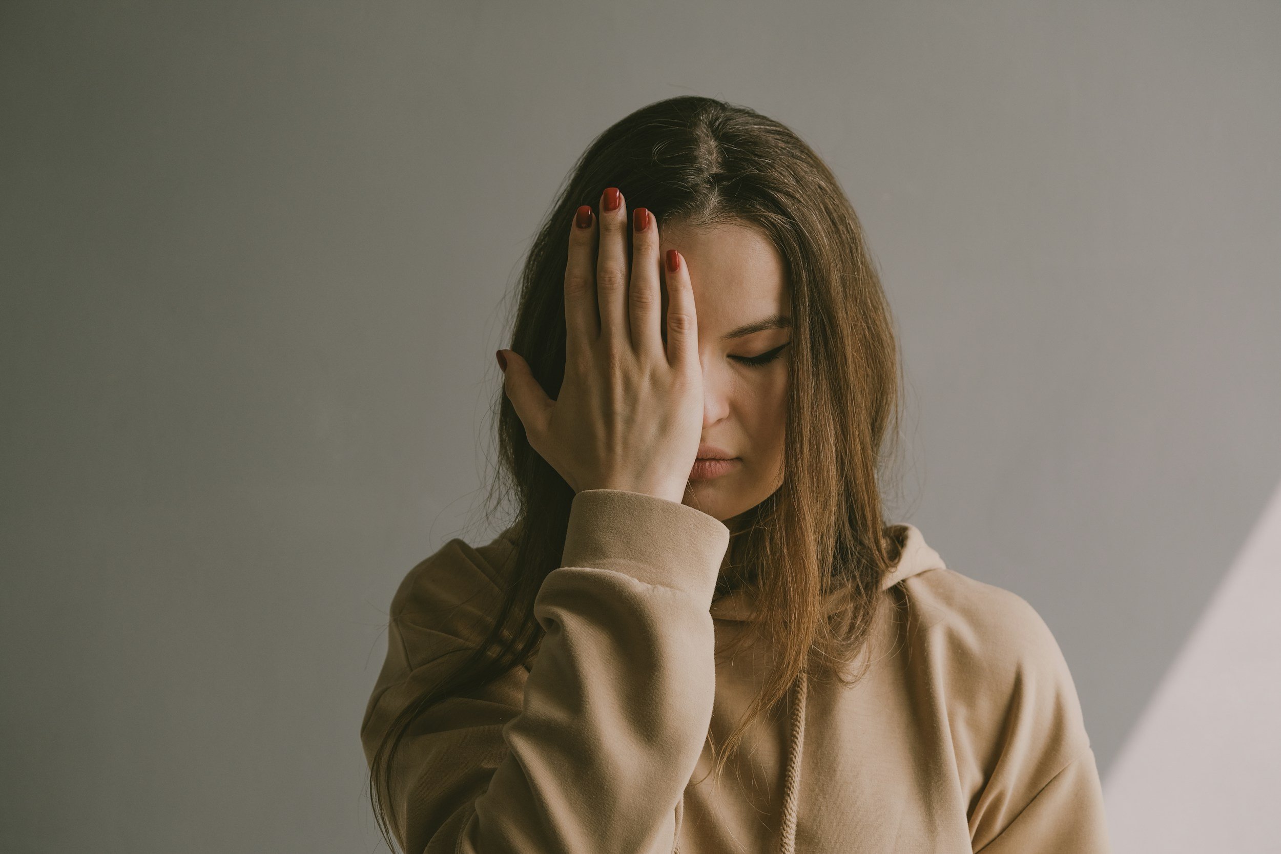 Woman covering one eye, looking defeated