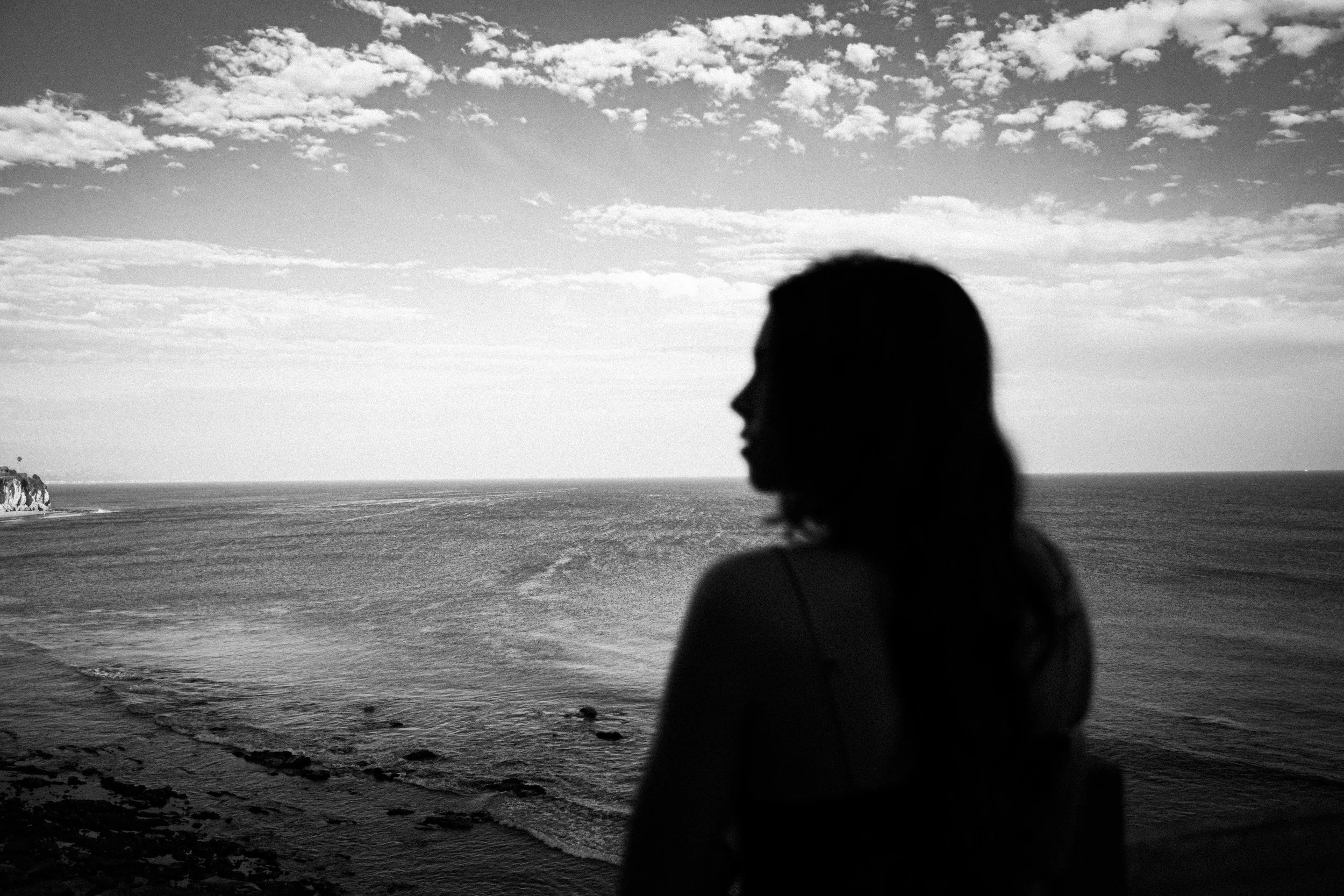 Silhouette of a woman looking out at the ocean while reflecting on self-awareness and changing old patterns