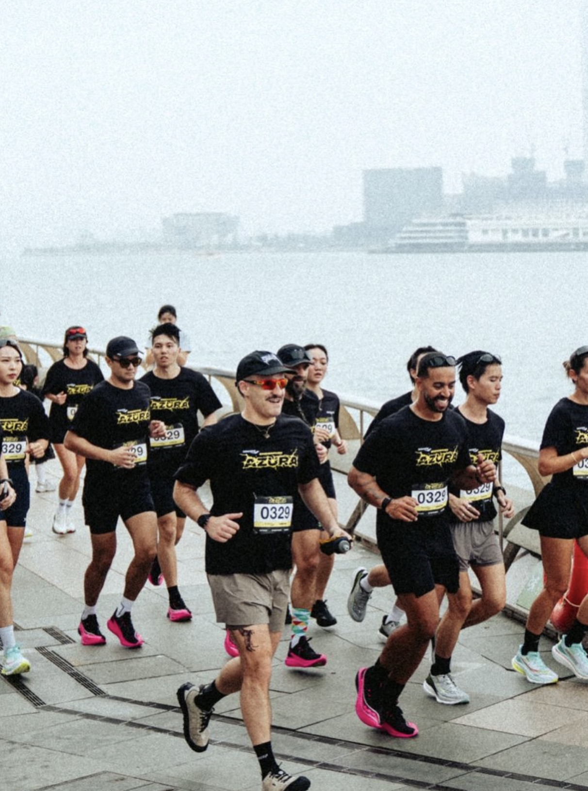 Run club crew in matching black tees racing along the Hong Kong waterfront — Social Goods Modern Bakery community partnership.