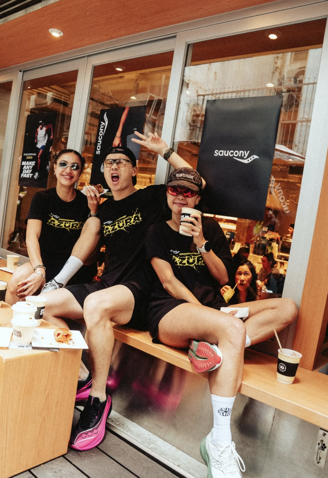Run club members post-race at Social Goods Modern Bakery Central with Saucony branded merchandise on display.