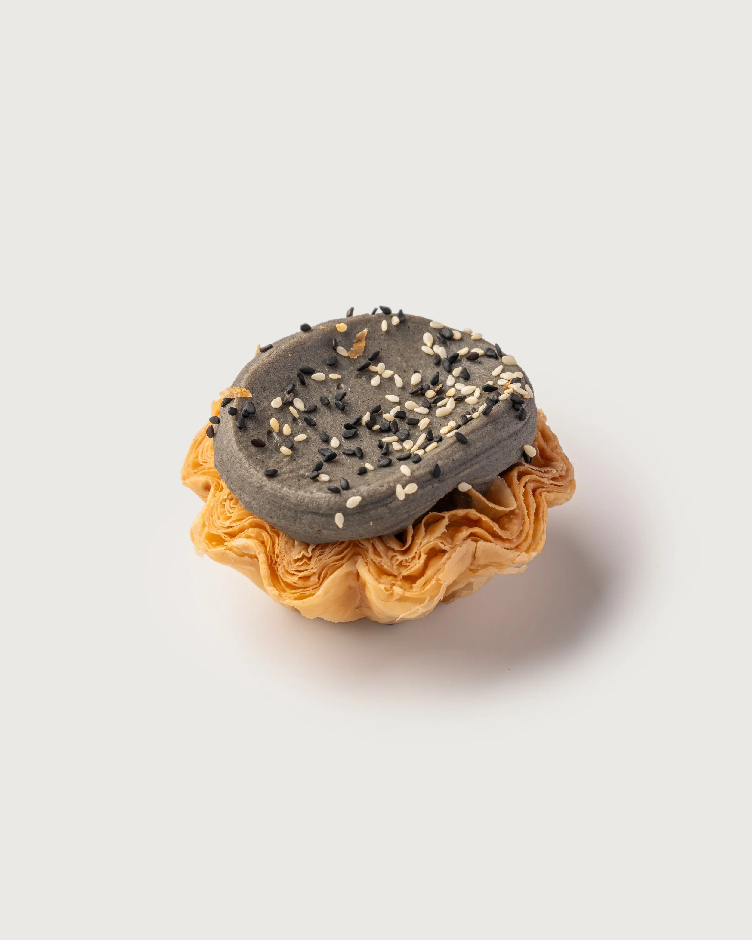 Sesame Mochi Tart — laminated base topped with sesame icing and black and white sesame seeds.