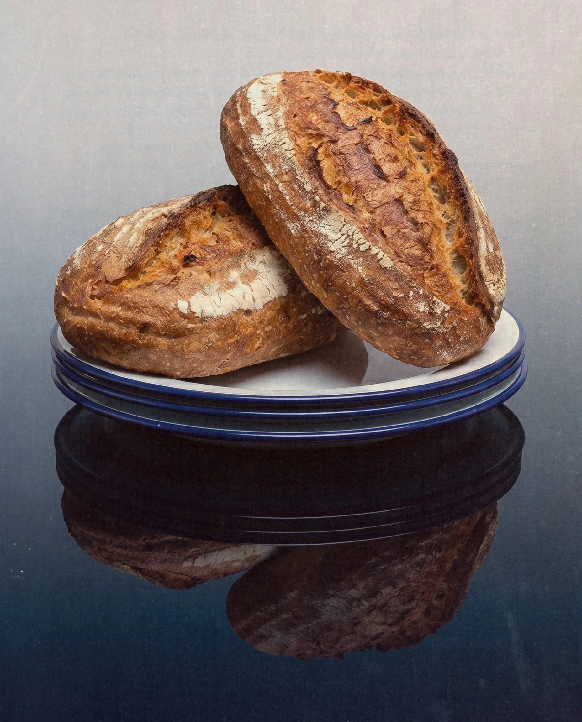 Two Classic Sourdough loaves on a glass plate — Social Goods Modern Bakery editorial.