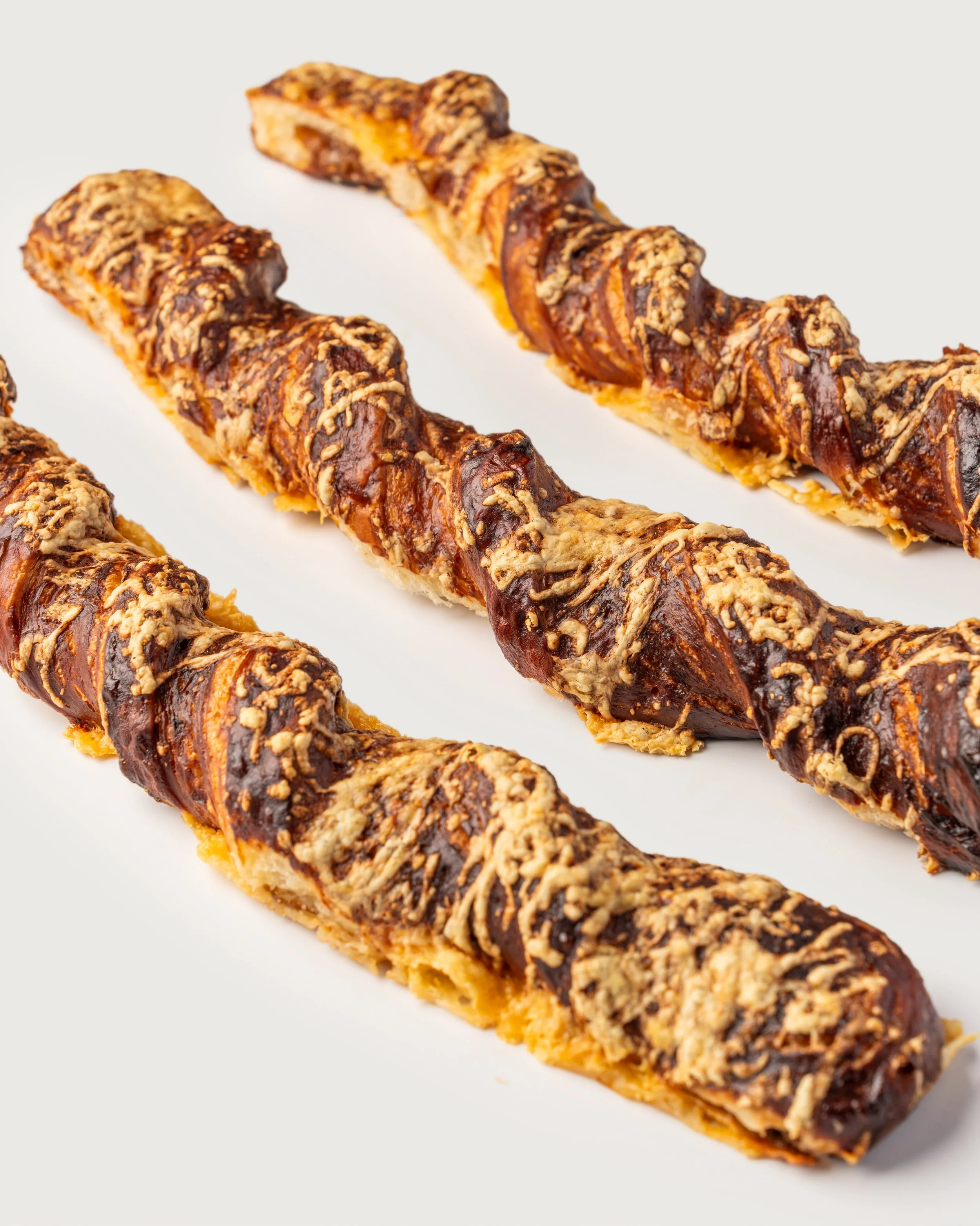 Three chocolate-covered churros sprinkled with crushed nuts on a white background.