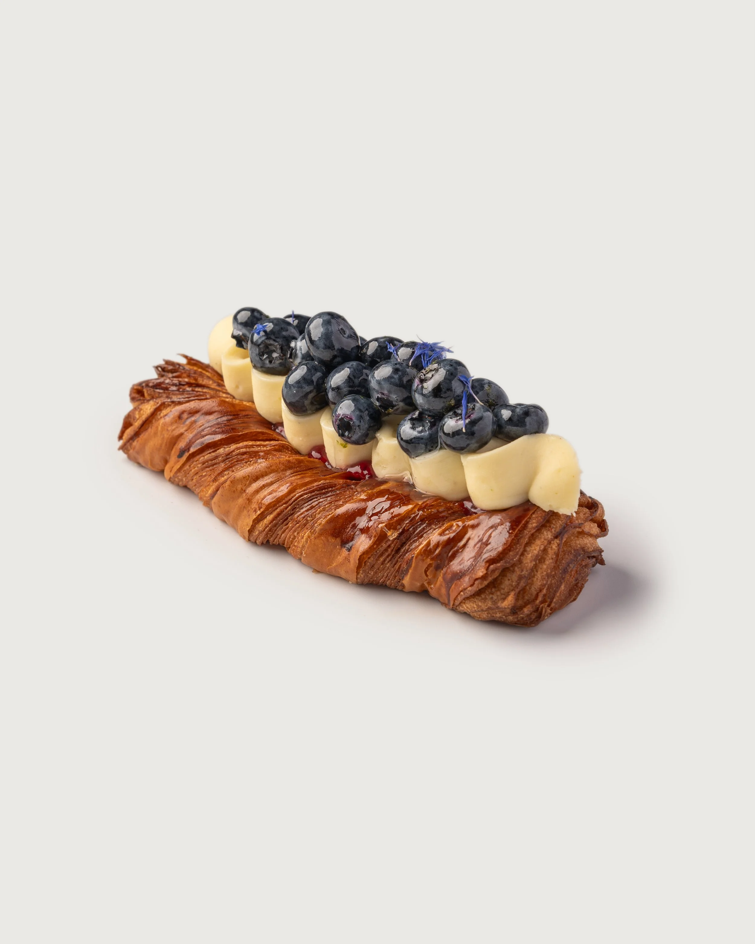 Blueberry Cream Jam Danish topped with white chocolate, fresh blueberries and edible flowers — Social Goods Modern Bakery.