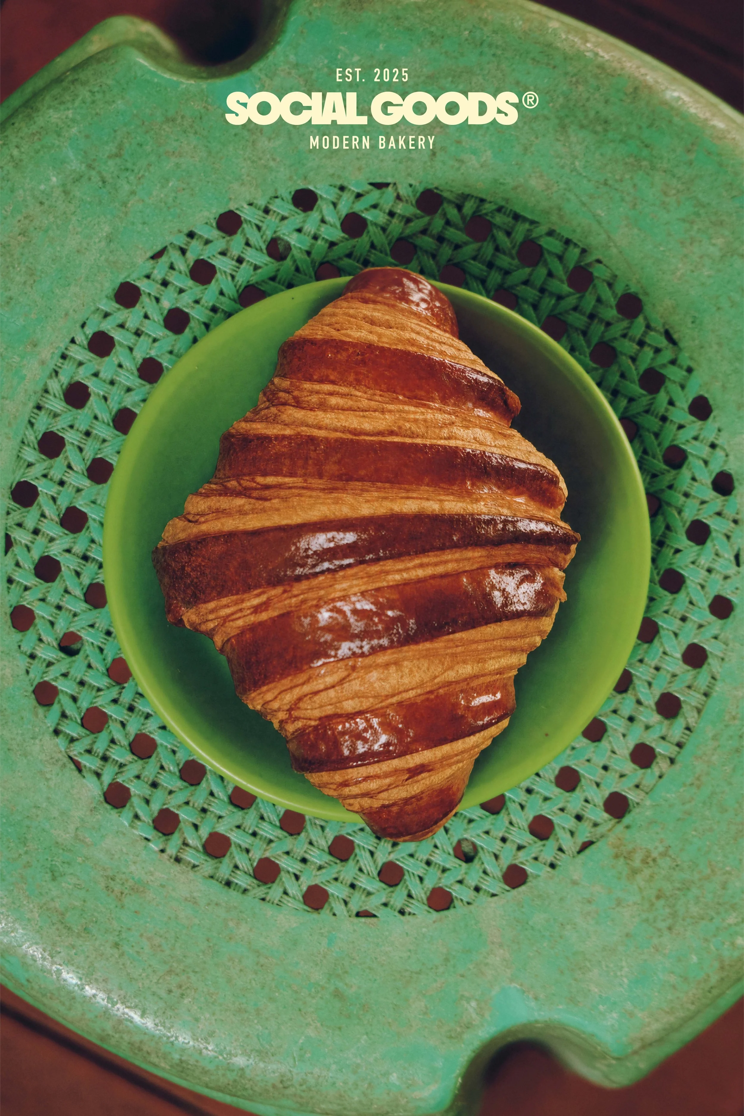 A croissant served in a green woven basket.