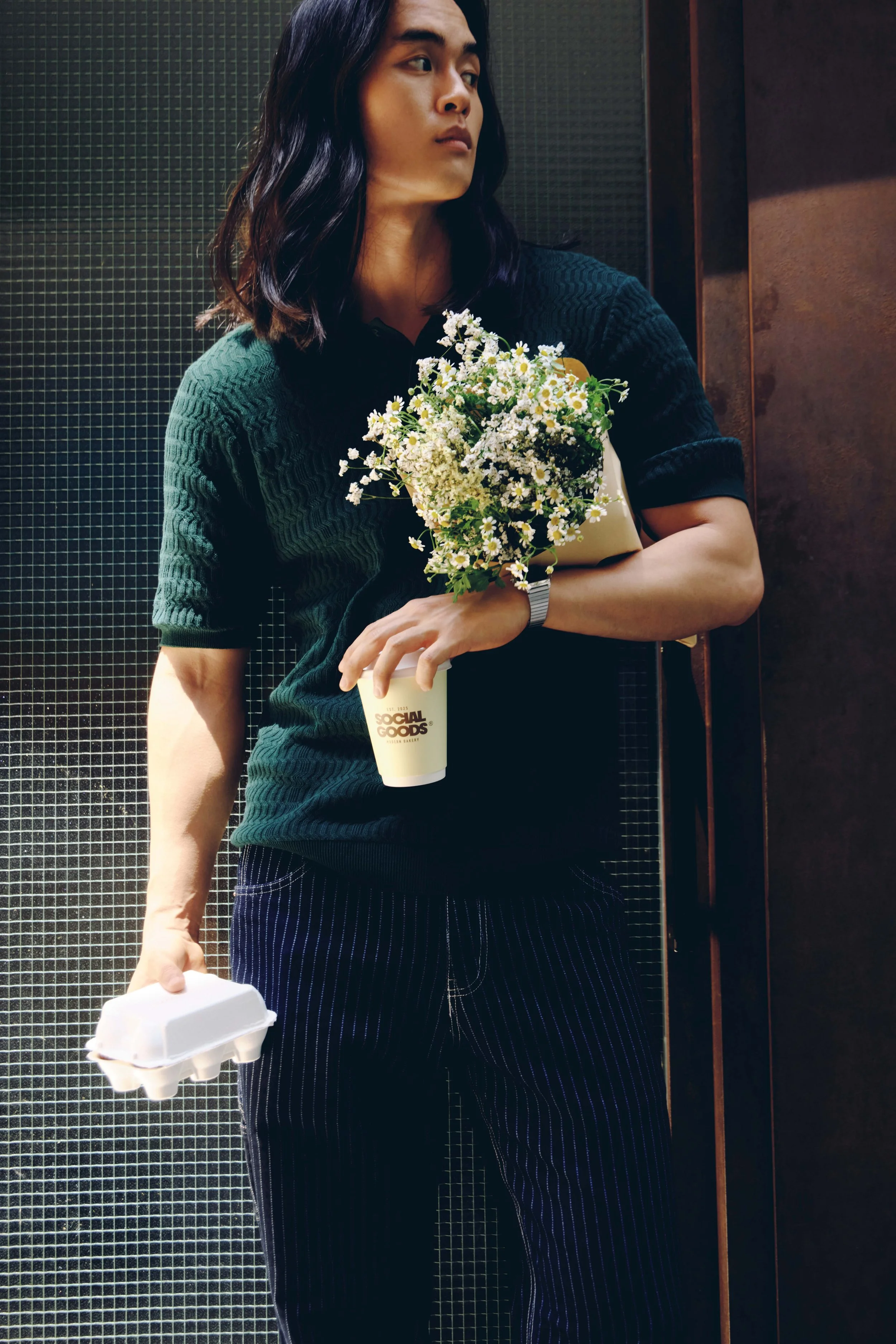 A woman stands in a lift holding flowers, a coffee cup, and a takeaway container, capturing everyday Hong Kong life.