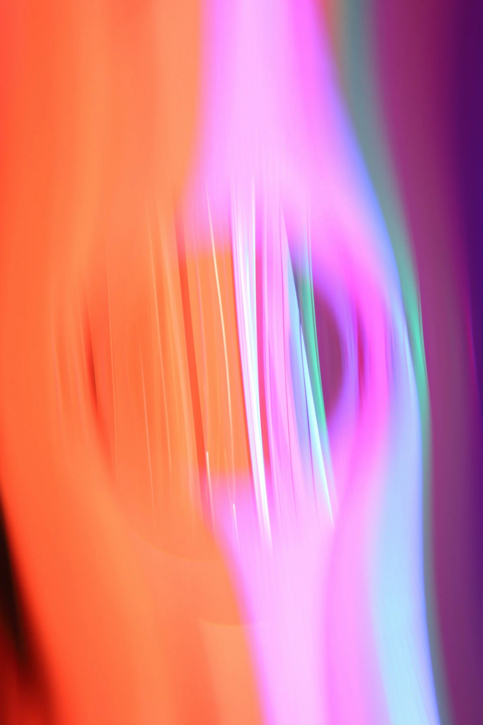 An abstract image with streaks of bright, colorful light in shades of orange, pink, purple, blue, and green.
