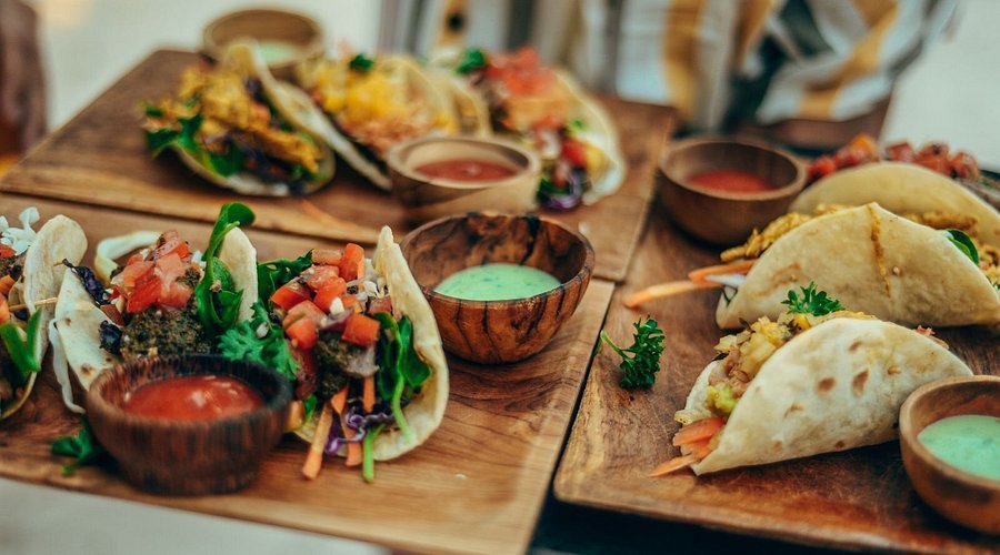 Three wooden platters with tacos, Mexican sauces, and garnishes.