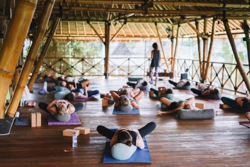 Group of people practicing yoga indoors on mats, with a instructor at the front.