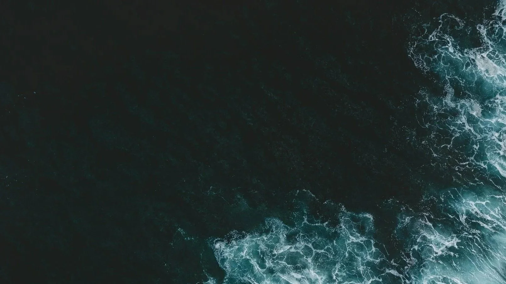 Aerial view of ocean waves crashing against rocks.